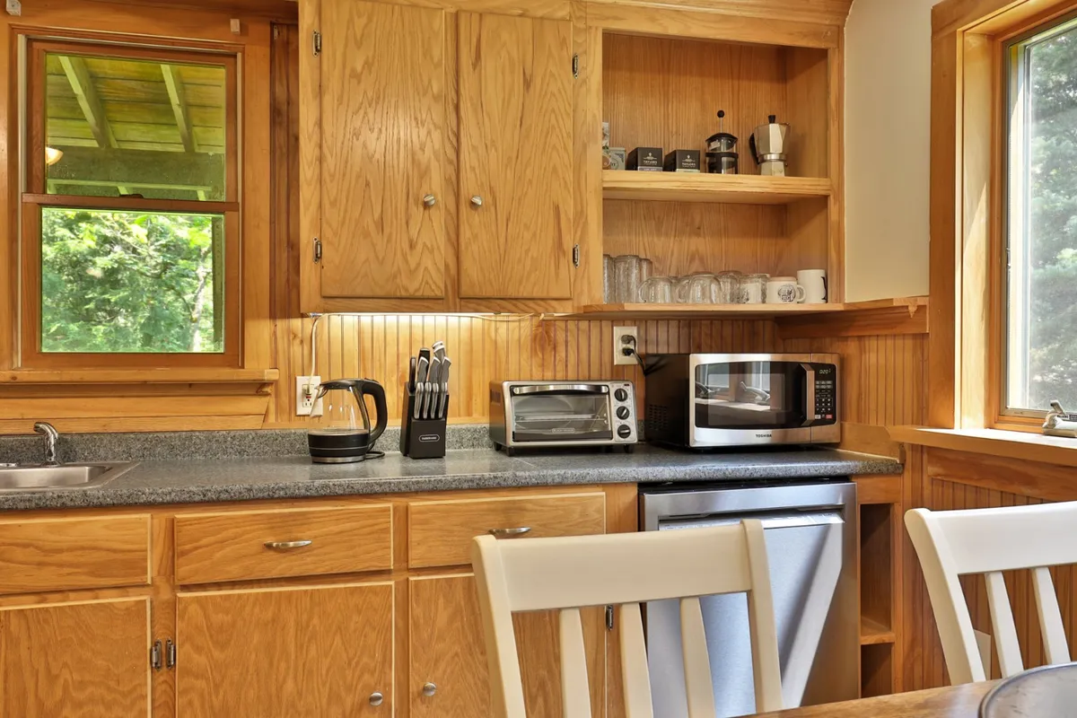 A cozy, welcoming kitchen with wooden cabinetry, countertop appliances, and a bright window overlooking the outdoors. The space is functional yet inviting, ideal for preparing meals or snacks before and after outdoor activities. The natural light and view through the window subtly hint at the connection between indoor comforts and the surrounding landscape.