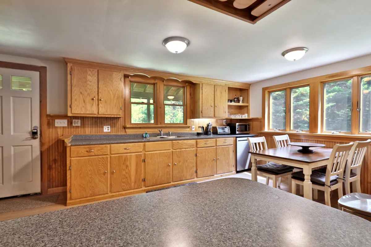 A warm and welcoming kitchen and dining area featuring modern cabinets, a spacious dining table, and large windows that let in natural light. The setup is ideal for both meal prep and enjoying meals together, with a cozy atmosphere that supports gathering and relaxation.